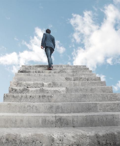 A man climbing stone stairs towards the sky